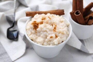 Tasty rice pudding with cinnamon served on white table, closeup