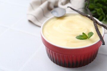 Tasty vanilla pudding, mint and pods on white tiled table, closeup. Space for text