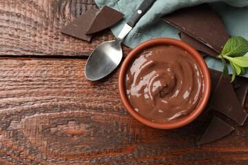 Tasty pudding with mint and pieces of chocolate served on wooden table, flat lay. Space for text