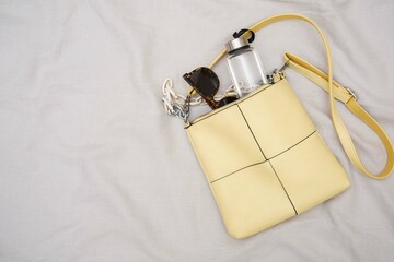 A trendy yellow handbag with fashionable sunglasses, a water bottle for your daily essentials.