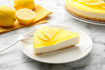 Piece of tasty lemon cheesecake and fork on white marble table, closeup