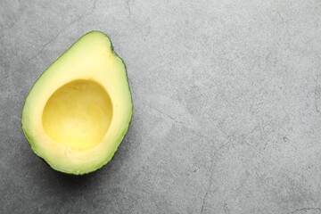 Half of ripe avocado on light grey table, top view. Space for text