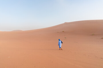 berber man walking in the desert of sahara on big sand dune in morocco landscape travel