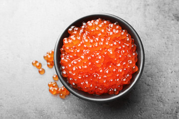 Tasty red caviar in bowl on grey table, top view