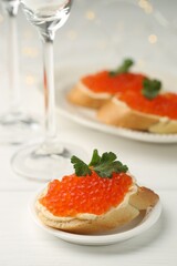 Tasty sandwiches with red caviar on white wooden table, closeup