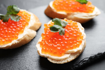 Tasty sandwiches with red caviar on grey table, closeup