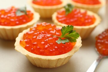Tartlets with red caviar and parsley on beige table, closeup