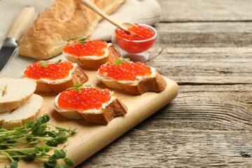 Sandwiches with red caviar and microgreens on wooden table, closeup
