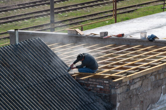 A man repairs the roof of a house
