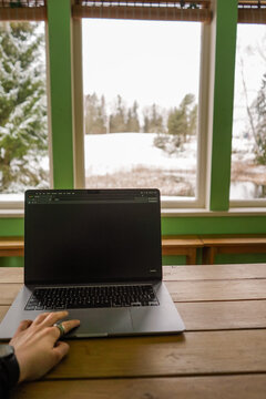 (POV) Point of view of remote working and typing on a laptop from a countryside house in winter with snow view in the background