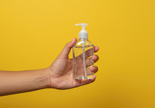 Hand holding antiseptic antibacterial disinfectant isolated on yellow background. Coronavirus protection