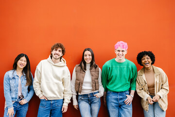 Happy multiracial young friends smiling at camera standing over isolated red urban background