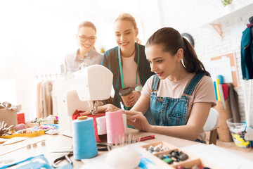 Fototapeta premium Three women at garment factory. One of them is sewing new dress.