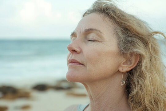 A Caucasian woman practicing breathwork exercises at the beach, focusing on relaxation and mental clarity.