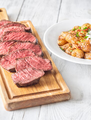 Juicy medium-rare steak with baked potatoes, crispy bacon, and melted cheddar