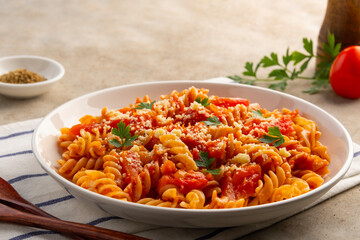 Fusilli macaroni with fresh tomatoes sauce in white plate.topped with parmesan cheese and parsley.
