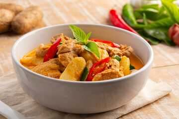 Thai red curry soup with pork and yam(Dioscorea esculenta yam),boiled sliced pork with red curry paste and coconut milk in white bowl.