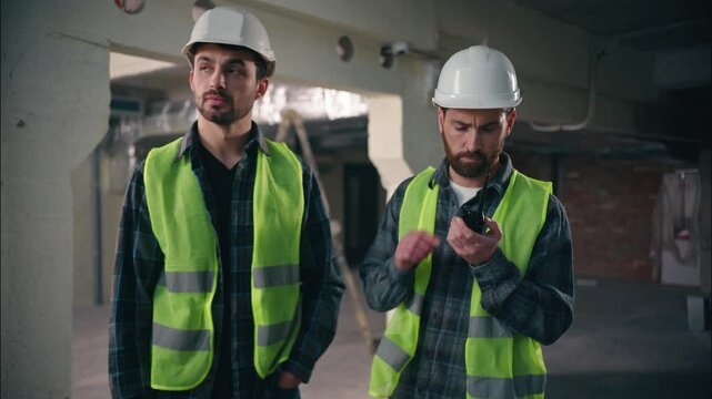 Caucasian men electricians builders guys architects males try speak walkie talkie broken device fail problem handymen foremen show new radio set tech mechanics communicate in construction manufacture