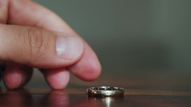 Close-up of hand tossing a wedding ring on a table. Betrayal and divorce concept. High quality 4k footage