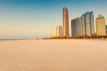 Scenic view of Abu Dhabi Corniche beach during sunrise with modern skyscrapers rising majestically in the background