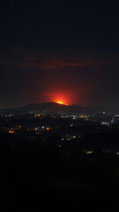 Naklejka premium Night scene with a bright red wildfire raging on a hillside above a city.