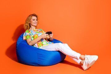 Smiling young woman with red curly hair wearing a colorful floral shirt, enthusiastically playing...