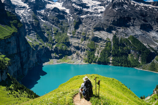 Switzerland travel - Senior man hiking looking at the scenic views  high above the Oeschinen lake in the Swiss Alps near Kandersteg.  