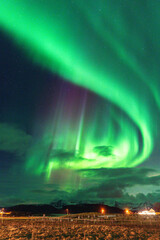 Beautiful Aurora Borealis over house on the island of Kvaløya, dancing northern lights with green light, red and purple strikes, clear colored rays of light in the sky, amazing joy in Norway
