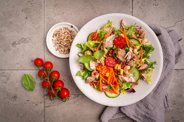 Salad with chicken meat on gray background, top view. Fresh vegetable salad with chicken. Meat salad with chicken fillet and fresh vegetables on plate. High quality photo