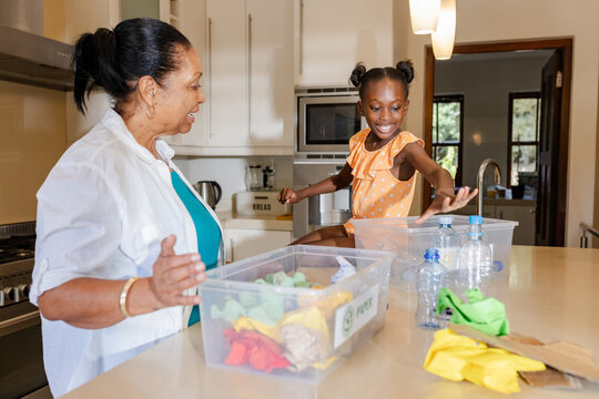 Sorting recyclables in kitchen, grandmother and granddaughter sharing quality time together