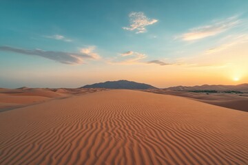 Expansive desert landscape at sunset highlighting undulating dunes and distant mountains under a vibrant sky