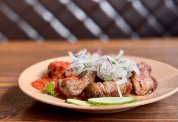 Savor the experience of Delicious Grilled Meat paired with Fresh Vegetables and flavorful Sauce. Enjoy grilled meat topped with crispy fried onions, rich tomato sauce, and crunchy cucumber slices