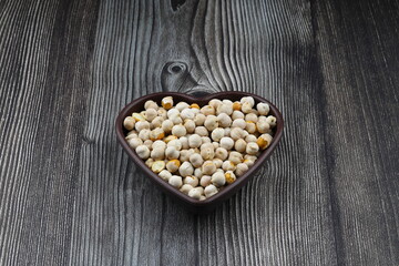 Roasted white chickpeas in wooden bowl on wooden background, top view. White chickpeas, with their high fiber content, are very healthy to consume.