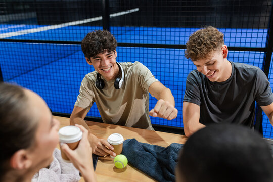 After padel tennis match, friends having coffee and chatting, smiling and relaxed