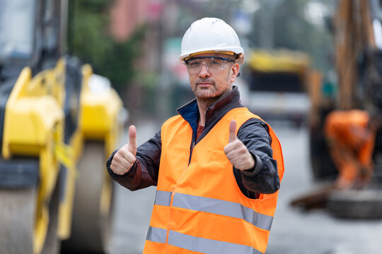 Construction worker giving thumbs up for safe progress at job site during a bright day