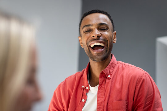 Smiling man in red shirt enjoying joyful moment at home gathering - Powered by Adobe