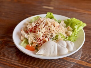 A Freshly Rendered Salad made with Crisp Lettuce and a Deliciously Creamy Dressing. A vibrant and colorful plate of fresh salad featuring tender shredded chicken, crisp lettuce, and a creamy side