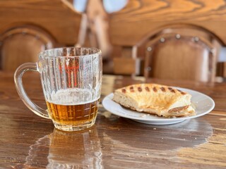 This scrumptious, golden brown flatbread features distinct and unique grill marks, making it ideal for any meal. A glass mug filled with golden beer sits on a rustic wooden table