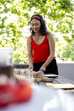 At party, Woman in red top preparing food on deck on sunny day, enjoying nature