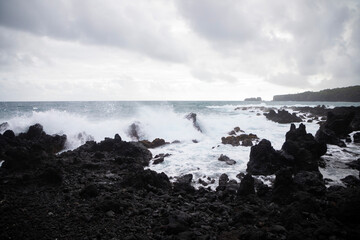 waves crashing into black rock beach