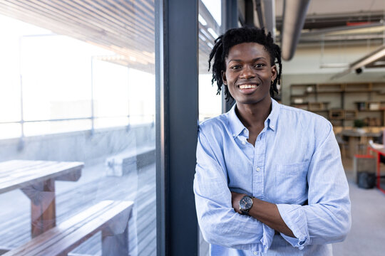 Confident young professional in casual shirt smiling in modern office space, copy space