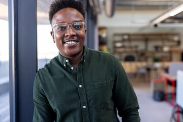 Smiling professional in green shirt standing confidently in modern office space