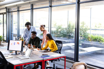 In office, diverse team discussing project, collaborating with charts on screen, copy space