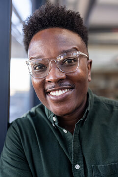 Smiling professional wearing glasses in office, exuding confidence and positivity