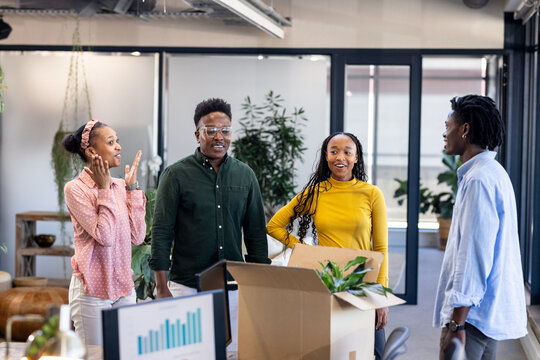 Diverse colleagues in office unpacking box, discussing new project with excitement - Powered by Adobe