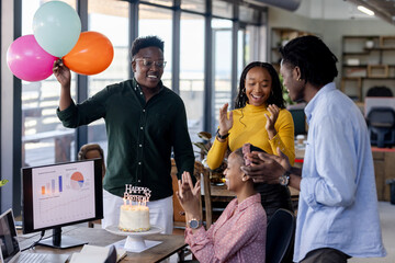 Celebrating birthday at office, diverse team clapping and smiling with balloons