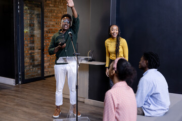 At office, speaking at podium, african american man with diverse colleagues listening, copy space