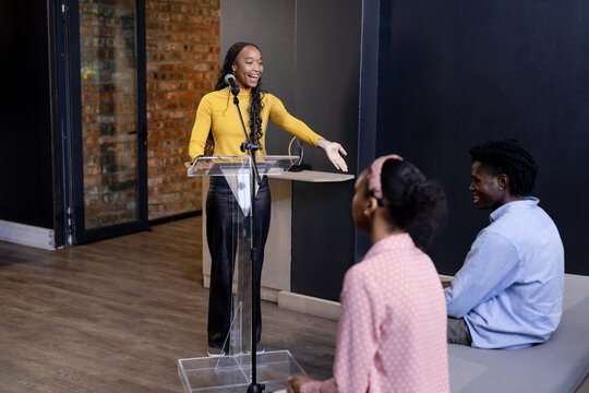 Woman presenting at podium engaging audience in modern office setting