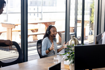 Young woman in office using headset, engaging in lively virtual meeting