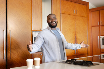 African American man in kitchen smiling with coffee cups on counter, feeling joyful, at home